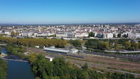 Luftaufnahme-Des-Pau-Bahnhofs,-Der-über-Den-Fluss-Fährt,-Mit-Der-Stadt-Im-Hintergrund